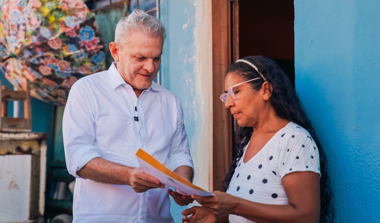 prefeito entregando o papel da casa para uma senhora